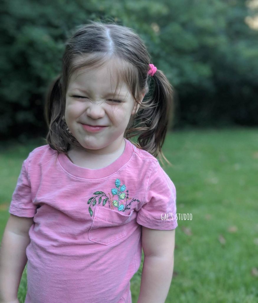 ילדה בחולצה רקומה עושה פרצוף מצחיק